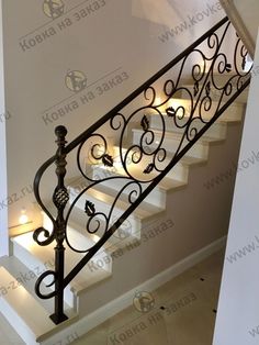 an iron stair railing with lights on the bottom and bottom handrails in white painted walls