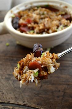 a spoon full of rice and vegetables on a wooden table