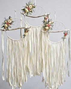 a white dream catcher with flowers hanging from it's sides