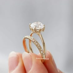 a person holding an engagement ring with a diamond in it's center and side stones on the band