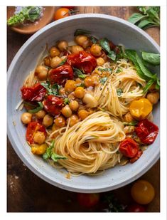 a white bowl filled with pasta and chickpeas on top of a wooden table