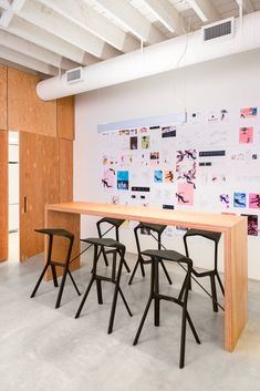 a long table with four chairs in front of it and a wall covered with pictures