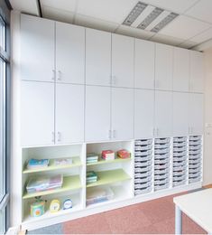 an office with white cabinets and shelves filled with files