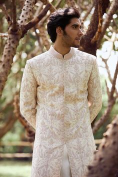 a man standing in front of some trees wearing a white and gold sherve