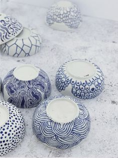 several blue and white vases sitting on top of a cement floor next to each other