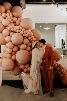 a man and woman standing next to each other in front of large balloons on the wall