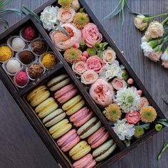 an open wooden box filled with lots of different types of macaroons and flowers