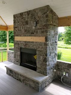 a stone fireplace in the middle of a porch