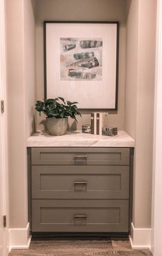 a white and gray dresser in a room with a painting on the wall above it