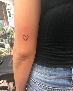 a woman with a small heart tattoo on her arm