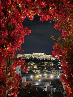 an arch with red flowers in front of the acrobatic castle at night