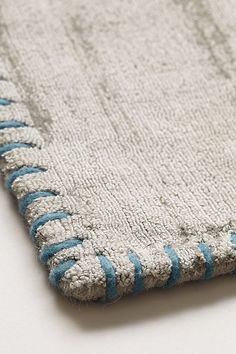 a white rug with blue and silver beads on the edges is laying on a table