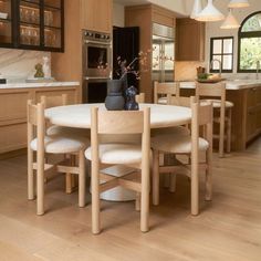 a table with four chairs around it in the middle of a large kitchen area that has wooden cabinets