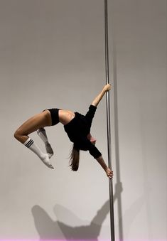 a woman standing on one leg while holding onto a pole