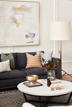 a living room filled with furniture and a painting on the wall above it's coffee table