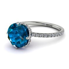 a blue diamond ring with diamonds around it and the words seigal written in white gold