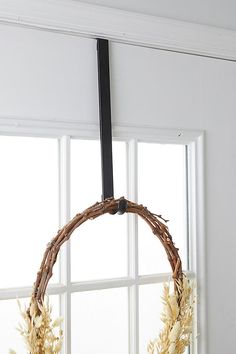 a wreath is hanging on the window sill in front of an open window with white curtains