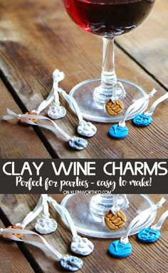 a glass of wine with the words clay wine charms in front of it on a wooden table