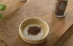 a wooden table topped with two cups filled with liquid