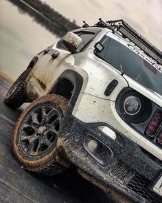 the front end of a white jeep with mud on it