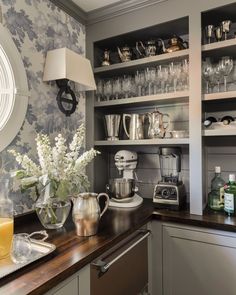 a kitchen counter topped with lots of silverware and cups next to a wall mounted clock