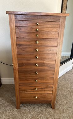 a wooden dresser with brass knobs in a room next to a mirror on the floor