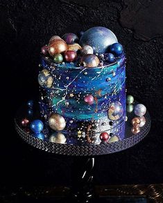 a three tiered cake decorated with colorful balls and stars on the top, sitting on a metal stand