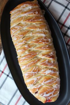 a loaf of bread sitting on top of a black plate next to a white and red checkered table cloth