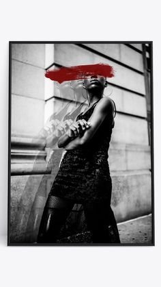 a black and white photo of a woman with a red umbrella over her head in front of a building