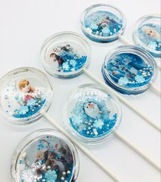 there are six frozen princess lollipops in the bowl with blue sprinkles