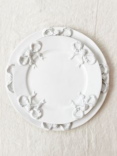 two white plates sitting on top of a table next to eachother with butterflies