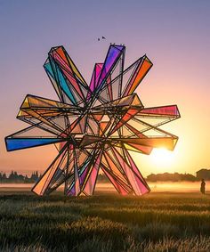 a sculpture in the middle of a field at sunset