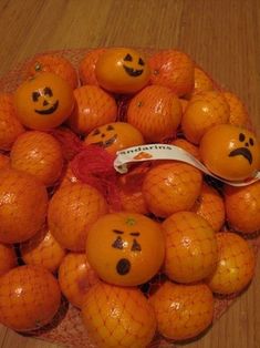 oranges with faces drawn on them sitting in a bowl