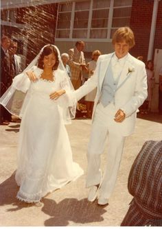 a man and woman in wedding attire walking down the street