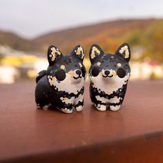 two black and white dog figurines sitting on top of a wooden table