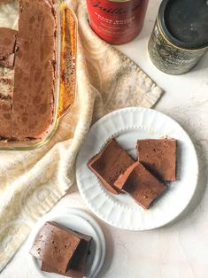 three pieces of chocolate cake sitting on top of a white plate next to a jar of peanut butter