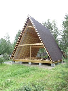 a frame house built in the middle of a field with grass and trees around it