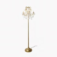 a gold floor lamp with crystal beads on the top and bottom arm, against a white background