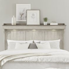 a bed with white linens and pillows in a gray room next to a framed photograph