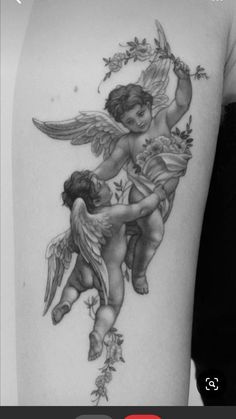 the back of a woman's shoulder with an angel tattoo on it and leaves