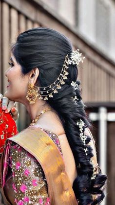 a woman with long black hair wearing a red and gold sari