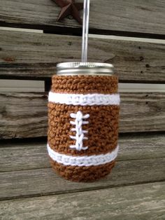 a crocheted mason jar with a football on the side and a straw in it