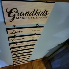 a wooden sign that says grandkids make life grand hanging from the ceiling in front of a door