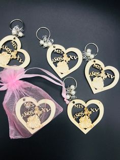 four wooden key chains in the shape of hearts with an angel on them and a pink organ bag