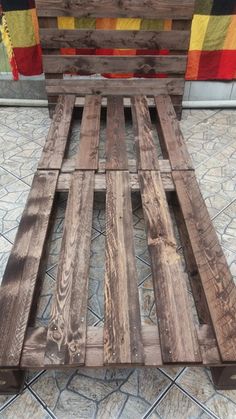 a wooden bed frame sitting on top of a tiled floor