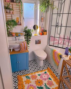 a bathroom with a sink, toilet and bathtub covered in colorful rugs next to a window