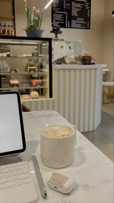 an open laptop computer sitting on top of a white table next to a cup of coffee