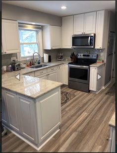 a kitchen with white cabinets and silver appliances