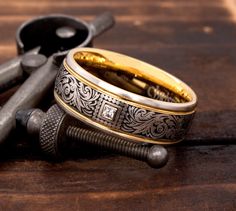 two gold and silver wedding bands sitting next to each other on top of a wooden table