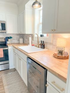 a clean kitchen with white cabinets and stainless steel appliances, including a dishwasher